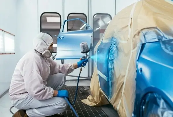 Man spraying car while wearing PPE
